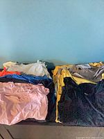 Stack of folded assorted clothing on surface showing multiple colours