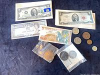 Overview of four banknotes and multiple coins on dark cloth