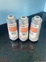 Three Toldi-Lock light gray thread cones standing on countertop