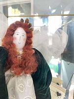 Close-up of doll’s face, hair, leaf crown and velvet sleeves with lace bodice