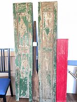 Front view of two green shutters, wood paddle, and edge of red shelf