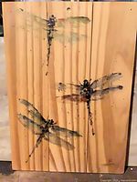 Full view of painting showing three dragonflies on wood slats