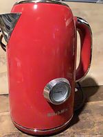 Front view showing red body, spout, handle, and overall condition