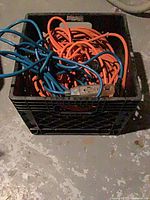 crate filled with coiled orange and blue extension cords