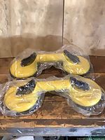 Two yellow double suction cup lifters in plastic sleeves, top view