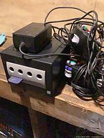 GameCube console front ports, power adapter, controller and cables visible