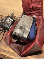 Camcorder in red carry case beside power adapter