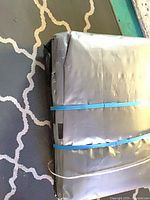 Folded gray tarp bundle secured with blue strap