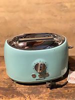 Front view showing overall toaster, dial, buttons, chrome top