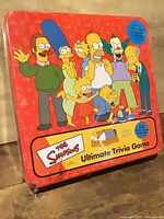 Front of sealed red tin showing The Simpsons Ultimate Trivia Game title and character artwork