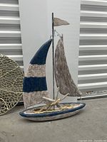 Wood sailboat sculpture with partial view of round metal wall art