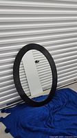 One of the black ribbed oval mirrors leaning against wall