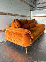 Full left-angle view of burnt orange velvet sofa showing three cushions, tufted front, wood legs