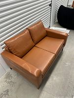 Full view of cognac leather loveseat showing overall style and condition