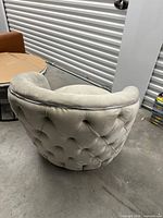 Rear view showing diamond-tufted back of light gray velvet barrel chair