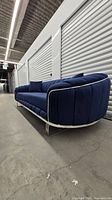 Full view of navy velvet sofa with chrome base and throw pillows