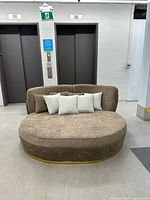 Front view of brown oval loveseat with five pillows