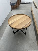 Top view of round wood table showing striped veneer and raised rim