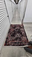 Dark grey/red abstract rug laid in hallway