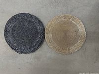 One navy-black and one beige-gold placemat side by side showing colors and pattern