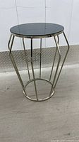 Side view of metal side table showing geometric frame and glass top