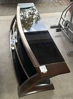 Top view of curved wood frame TV stand with black glass shelves