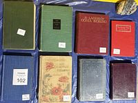 All eight books laid flat showing front boards