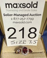 Front view of yellow-tone ring showing center oval garnet, two side pear garnets, clear accent stones