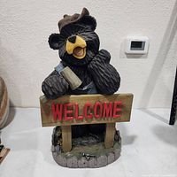 Front view of bear statue holding welcome sign