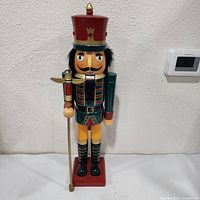 Front view of painted wooden nutcracker with staff