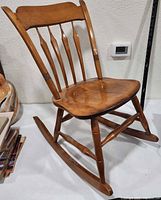 Front view of child’s wooden rocking chair showing spindle back, contoured seat and runners