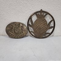 Both brass pineapple plaques side by side