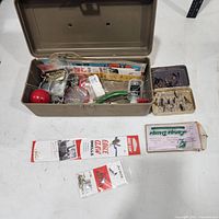 Overview of open metal tackle box, fly box, packaged hooks