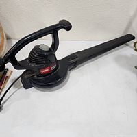 Left side view of black Toro corded electric leaf blower showing handle, motor housing, nozzle, power cord