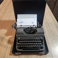 Typewriter in open case with paper inserted, full view