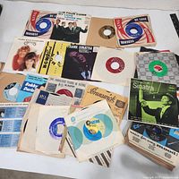 Group shot of approximately 25 45 RPM records with various sleeves