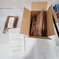 Open box with pre-cut wood pieces and instruction sheet