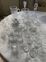 Assorted crystal glasses, decanters, pitcher, vase laid out on table