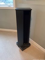 Full view of black rotating CD tower near wall