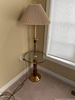 Full view of floor lamp showing shade, pole, glass table, base and cord