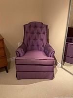Front view of purple tufted armchair with skirt