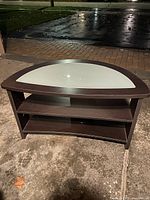 Front view of semi-circular TV stand showing glass top and shelves