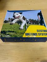 Front of retail box with product name Electric Dog Fence System and running dog image