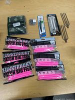All items laid out: six pink bait packs, two gig spears, lure, swivel kit, camouflage fabric