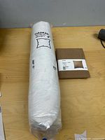 Rolled white Fjadrar pillow insert beside folded brown Dytag cover on table