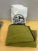 Olive green blanket folded beside River Co bag