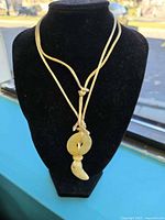 Full view of necklace on display bust showing amber pendant and cord