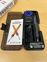 Kit in open case showing iron, cable, stand, flux, spool holder, manual