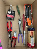 Top view showing pliers, screwdriver, ratchet, packaged utility knife and dies