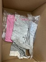 Box interior with pink and grey bagged garments